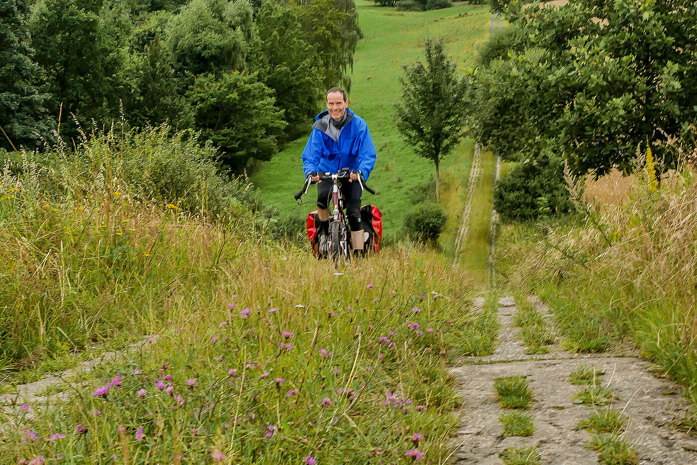 Auf dem ehemaligen Kolonnenweg der DDR-Grenztruppen im Vogtland/Sachsen. Radfahrer, Betonplattenweg, grüne Landschaft