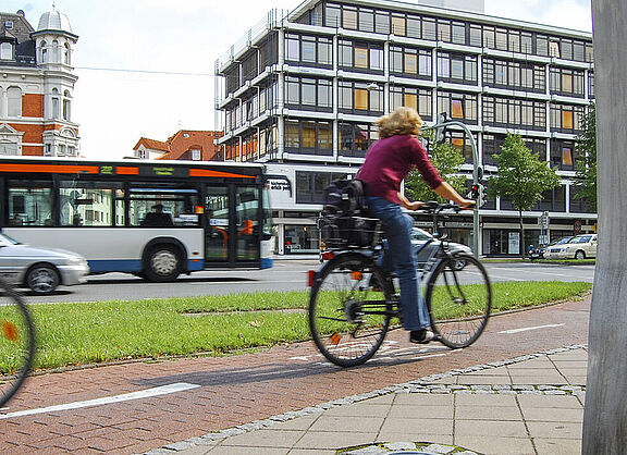 Radfahrende, Autos und Bus