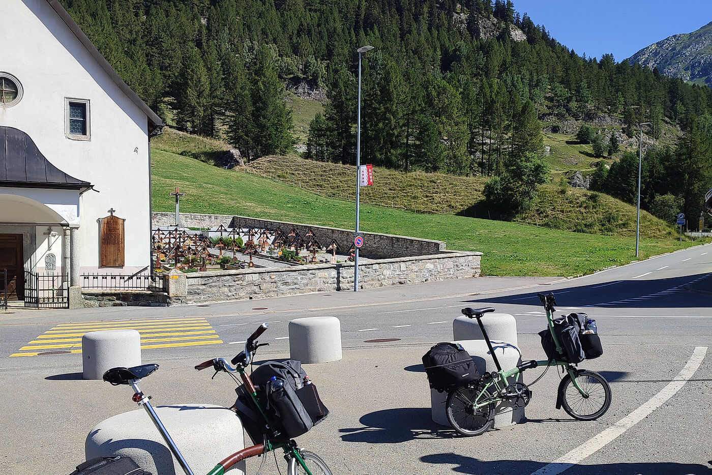 Entlang der Rhone aus den Alpen ans Mittelmeer: Pause in Oberwald (Schweiz) nach der anspruchsvollen Abfahrt mit den Bromptons vom Furkapass entlang der Furkastraße. zwei angelehnte Brompton-Falträder während einer Pause in Oberwaöd in der Schweiz