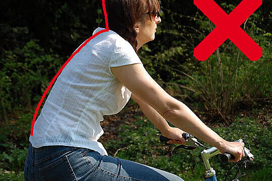 Frau sitzt mit gebeugtem Rücken auf Fahrrad