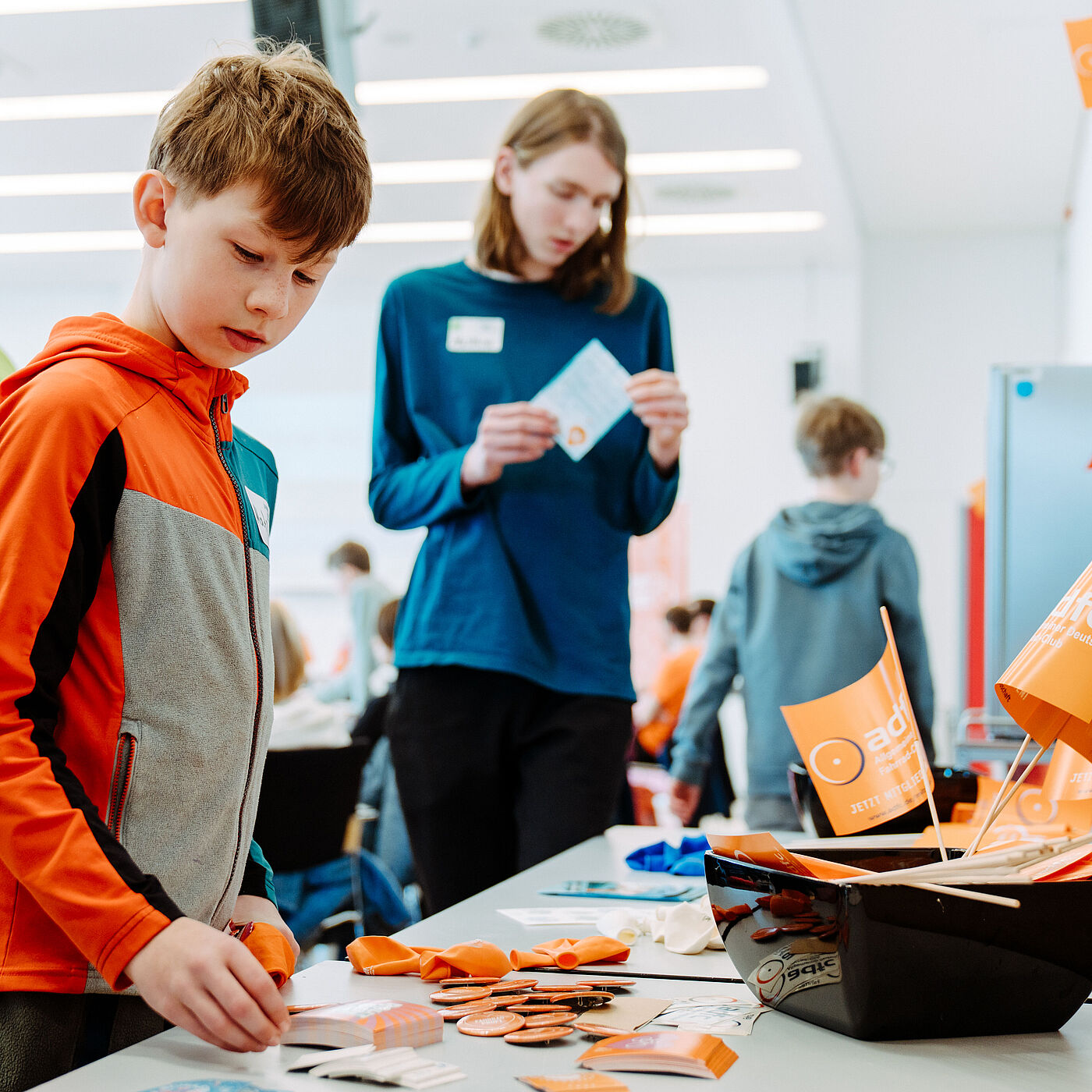 Am Goodie-Tisch Teilnehmende bei der Landesjugendversammlung 2026 begutachten am Goodie-Tisch Sticker, Buttons, Flyer und weitere Kleinigkeiten.