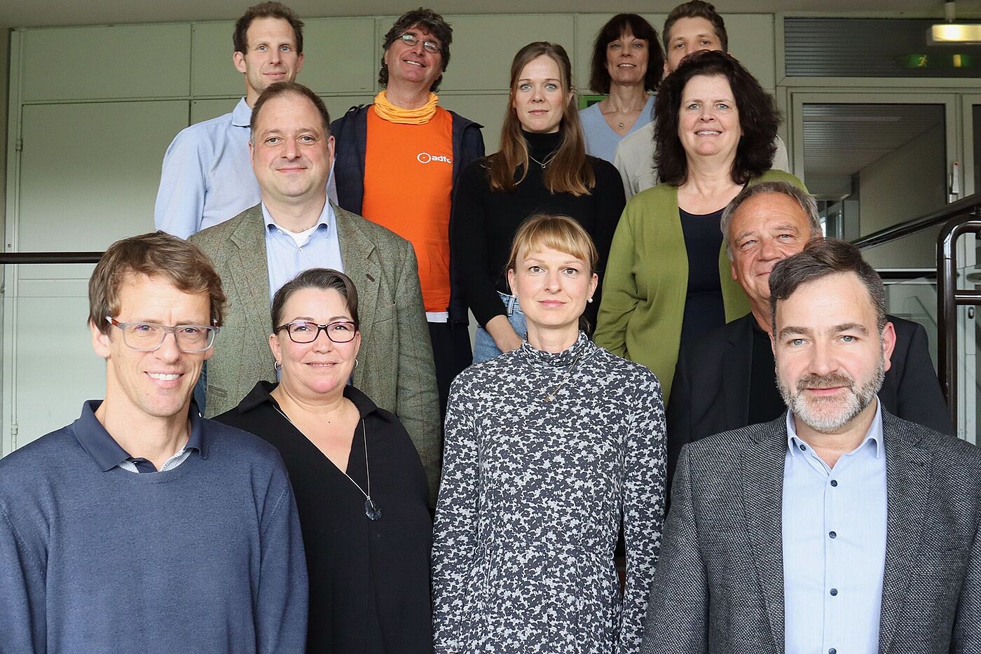 2024_11_04_FFA_BASt_c_BASt Zwölf Menschen stehen auf einem Podest. Man sieht nur ihre Oberkörper. Im Hintergrund ist eine Schrankwand zu erkennen.
